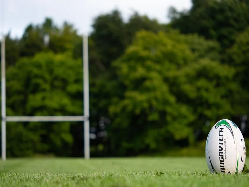 Ballon de rugby posé sur la pelouse devant les poteaux